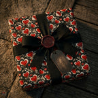 Vintage red heart wrapping paper on a luxury gift box with a black ribbon bow by Wrapped Studios.