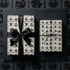 Gothic wrapping paper with vintage skulls and black ribbon. Spooky Halloween gift wrap by Wrapped Studios.