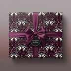 Elegant gift with a dark purple moth and moon pattern wrapping paper, tied with a satin ribbon.