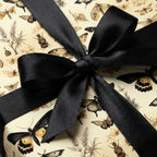 Elegant gift wrapped in entomology-themed paper with black satin ribbon.