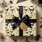 Gift box wrapped in vintage insect and butterfly print wrapping paper with black ribbon.