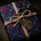 Elegant gift wrapped in navy floral wrapping paper, tied with rustic twine, and a leather gift tag.