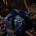 Luxury gift wrapped in moody floral and raven print paper with a velvet bow by Wrapped Studios.