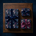 Gothic floral wrapping paper with crows on luxury gift boxes, tied with elegant velvet ribbons by Wrapped Studios.