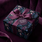Luxury gift box wrapped in gothic floral and raven pattern paper with a purple ribbon bow from Wrapped Studios.