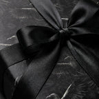 Gothic black raven wrapping paper with a satin bow, moody luxury gift wrap by Wrapped Studios.