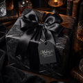 Dark elegant gothic wrapping paper with feather pattern and large black satin bow by Wrapped Studios.