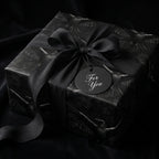 Luxury gothic raven wrapping paper with black satin bow and "For You" tag by Wrapped Studios.