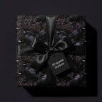 Gothic crow wrapping paper with a black satin bow on a luxury gift box by Wrapped Studios.