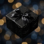 Gothic raven wrapping paper on a luxury gift box with a black satin bow, by Wrapped Studios.
