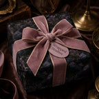 Gothic raven wrapping paper with dusty rose velvet ribbon on a luxury gift box by Wrapped Studios.