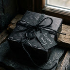 Gothic raven wrapping paper on a gift box with black twine and wax seal, by Wrapped Studios.