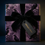 Elegant gift with dark floral wrapping paper featuring ravens, velvet ribbon, and "Midnight Aviary" tag.