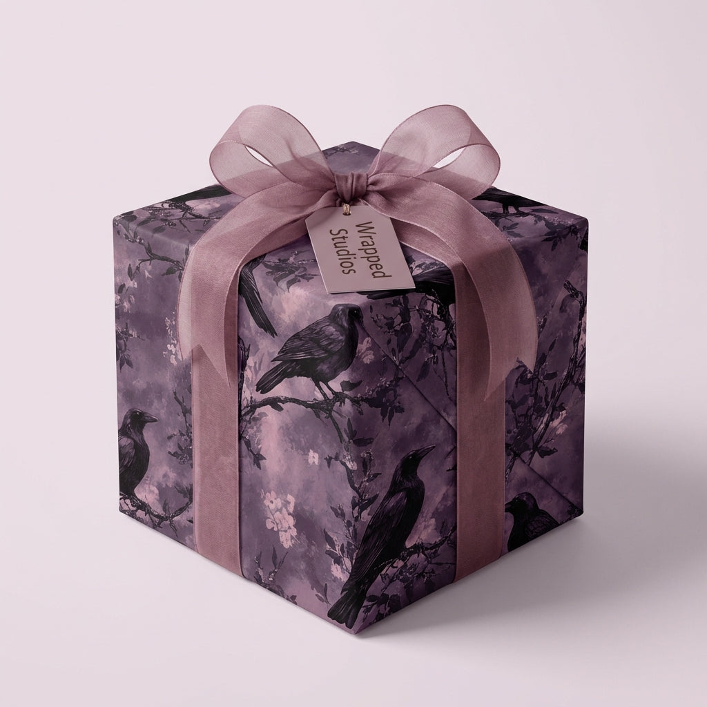 Elegant gift wrapped in moody floral paper with ravens, tied with a mauve ribbon.