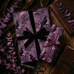 Elegant gothic gift wrap with a raven and floral pattern, tied with a black velvet ribbon.