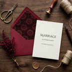 Elegant burgundy wedding invitation with vintage rosette envelope liner by Wrapped Studios on rustic wood.