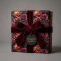 Luxury rose floral wrapping paper with a burgundy velvet bow on a gift box by Wrapped Studios.