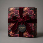 Luxury rose floral wrapping paper with a burgundy velvet bow on a gift box by Wrapped Studios.