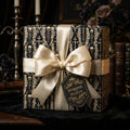 Gothic skull wrapping paper in black and gold with a luxury satin bow on a gift box by Wrapped Studios.