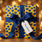 Yellow graduation wrapping paper with blue caps, a navy ribbon, and 'You Did It' tag by Wrapped Studios.