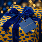 Blue and gold graduation wrapping paper with velvet ribbon and congratulations tag by Wrapped Studios.