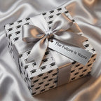 Graduation wrapping paper with black caps, silver bow, and 'The Future is Yours' tag by Wrapped Studios.