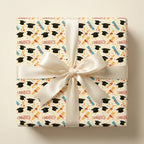 Congrats graduation wrapping paper with black caps, tied with a cream satin ribbon bow by Wrapped Studios.