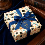 Graduation wrapping paper with caps and diplomas, tied with a blue ribbon and congrats tag by Wrapped Studios.