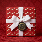 Red graduation wrapping paper with diploma pattern, white ribbon, and Congrats Grad tag by Wrapped Studios.