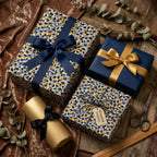 Luxury gift boxes wrapped in modern navy, gold, and white confetti paper from Wrapped Studios with satin ribbon bows.