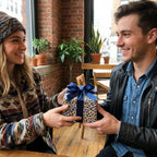 Couple exchanging a gift in modern blue and yellow patterned wrapping paper with a navy blue ribbon from Wrapped Studios.