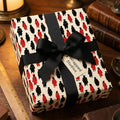 Graduation wrapping paper featuring red and black graduates with a black bow by Wrapped Studios.
