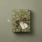 Olive green gift wrap with a geometric mosaic pattern and ribbon; mystery gift tag with question mark.