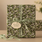 Olive green gift box wrapped in modern square pattern paper with sheer ribbon bow.