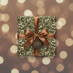Square gift wrapped in modern geometric paper with brown ribbon and gold bokeh background.