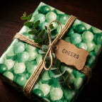 Green balloon birthday wrapping paper with rustic twine and a cheers tag by Wrapped Studios.