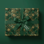 Luxury emerald green and gold wrapping paper with a matching ribbon and bow on a gift box by Wrapped Studios.