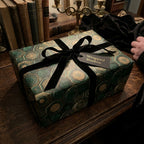 Luxury green and gold vintage wrapping paper with a black velvet bow on a gift box by Wrapped Studios.