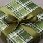 Square gift wrapped in green plaid wrapping paper with a matching green satin ribbon.