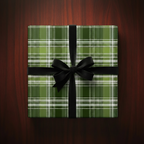 Green plaid wrapping paper with a black velvet bow on a square gift box.