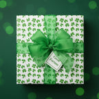 Square gift wrapped in clover-patterned paper with green ribbon and "Good Fortune" tag.