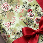 Sage green floral wrapping paper with a red satin bow. Vintage Christmas gift wrap by Wrapped Studios.