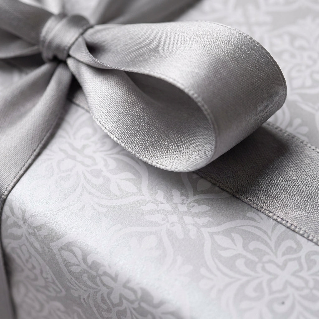Elegant silver damask luxury gift wrap with a satin ribbon on a wedding present by Wrapped Studios.