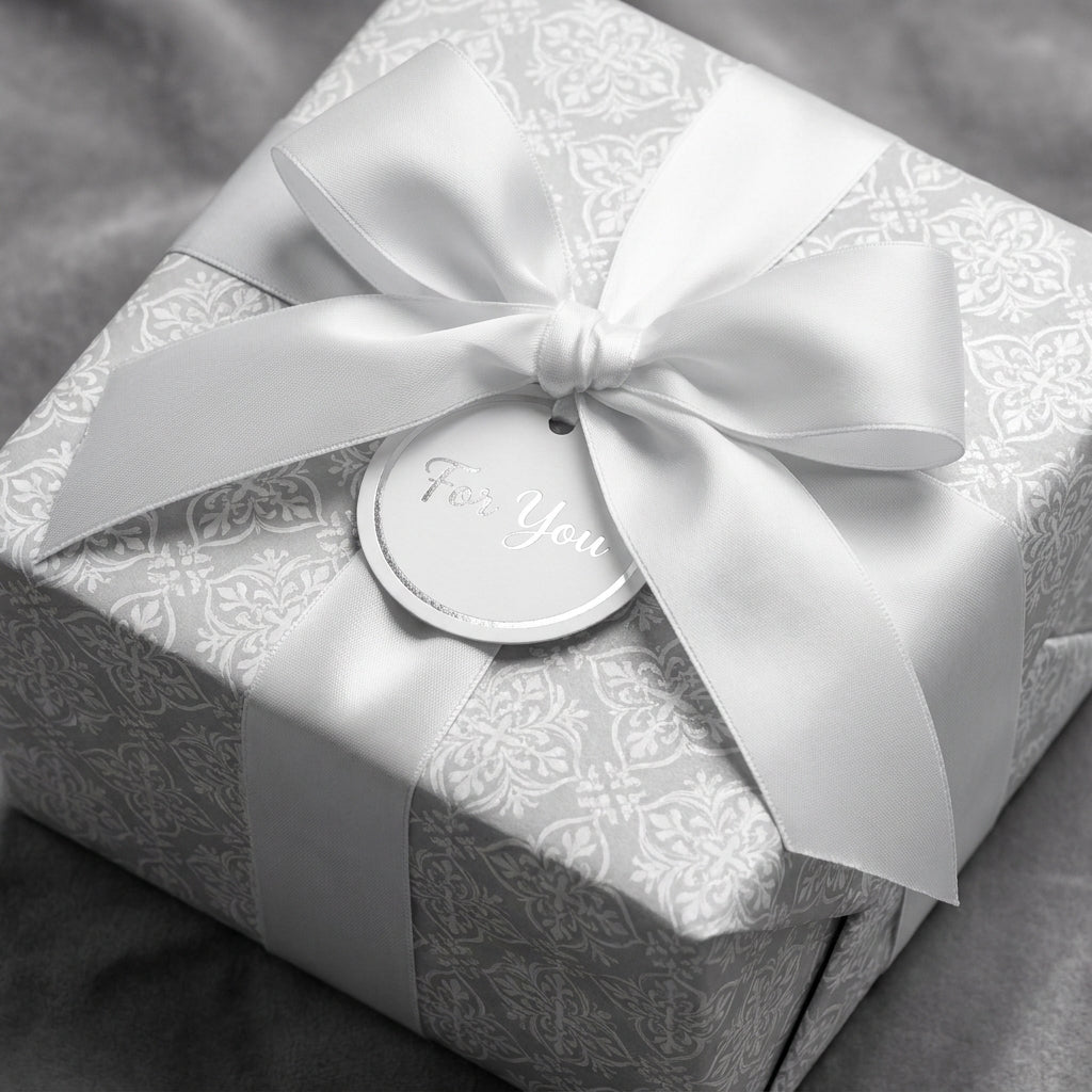 Elegant silver damask wrapping paper with white satin bow and 'For You' gift tag by Wrapped Studios.