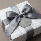 Elegant silver damask wrapping paper with a grey satin bow on a wedding gift box by Wrapped Studios.