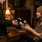 Gothic skull wrapping paper with a black velvet bow on a gift being exchanged, by Wrapped Studios.