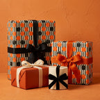 Modern orange and black polka dot wrapping paper on gift boxes by Wrapped Studios.