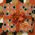 Retro orange and black striped polka dot wrapping paper with a rust bow by Wrapped Studios.