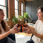 Couple sharing a gift in orange and black Halloween wrapping paper with stripes and dots, by Wrapped Studios.