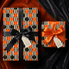 Orange and black striped Halloween wrapping paper with polka dots and bows by Wrapped Studios.